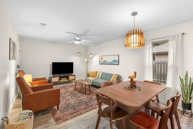 a view of a livingroom and dining room with furniture wooden floor a chandelier