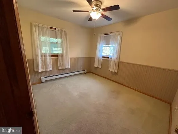 an empty room with windows and fan