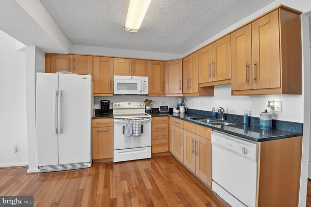 a kitchen with granite countertop white cabinets and white appliances