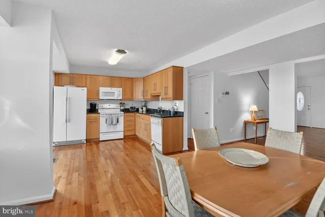 a kitchen with stainless steel appliances granite countertop a refrigerator a stove top oven a sink dishwasher and white cabinets with wooden floor