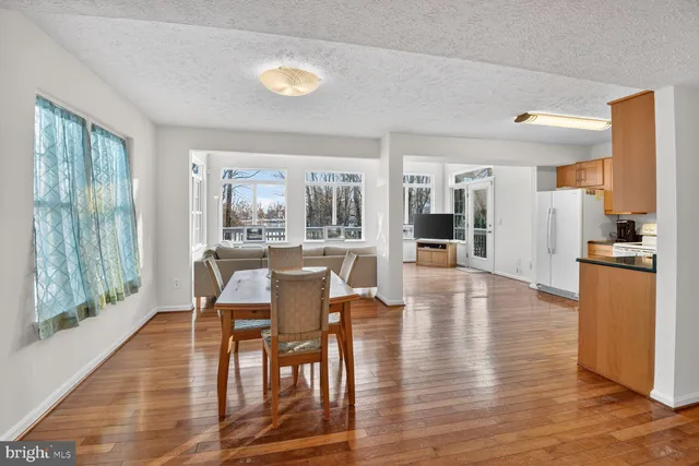 a dining room with wooden floor and large windows