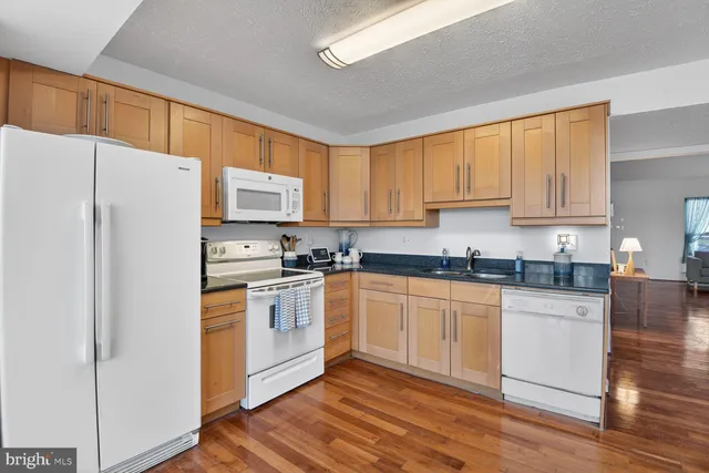 a kitchen with granite countertop white cabinets and white appliances