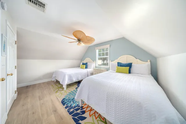 a bedroom with two beds and a lamp with the wooden floor