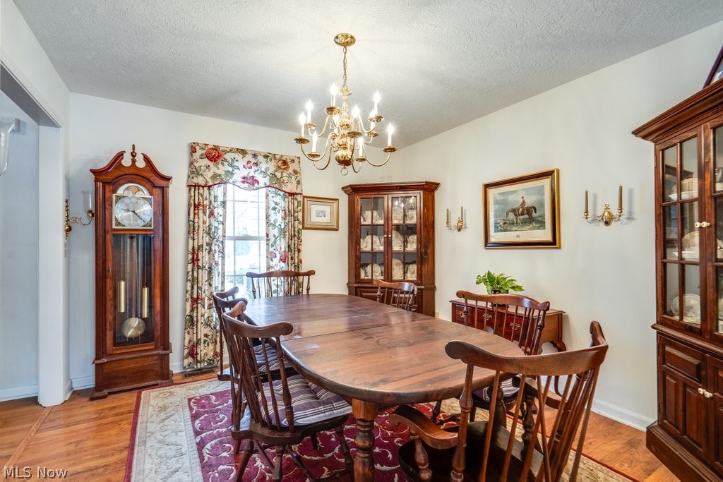 136 Taylor Road Barberton, OH 44203 - Photo 6 of 45 Dining room featuring a chandelier, a textured ceiling, and light wood-style floors
