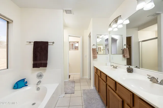 a spacious bathroom with a double vanity sink mirror and bathtub