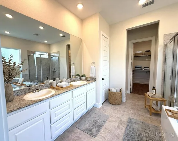 a bathroom with a granite countertop sink and mirror with bathtub