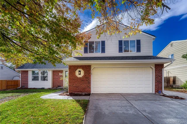a view of a yard in front of a house with plants and large tree