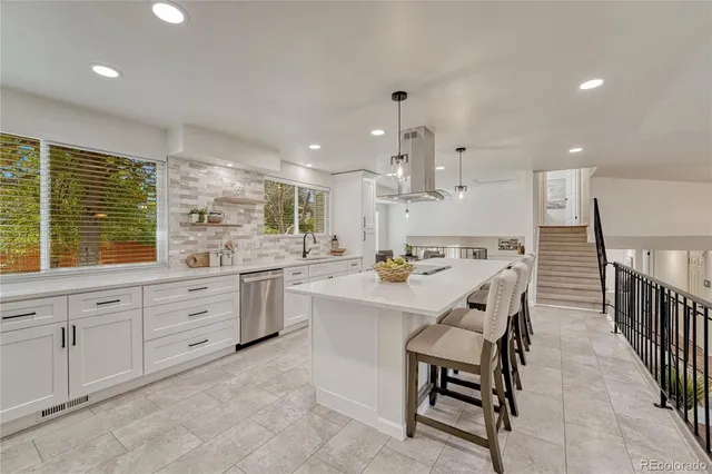 a large kitchen with kitchen island a sink a stove a dining table chairs and mirrors