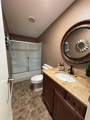 a bathroom with a granite countertop toilet sink and mirror
