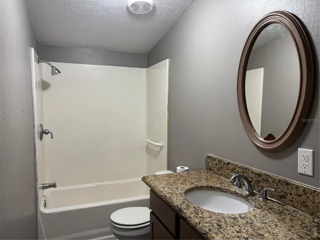 a bathroom with a granite countertop sink toilet and a mirror