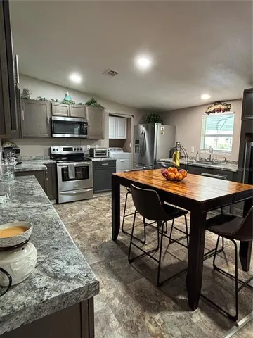 a kitchen with stainless steel appliances granite countertop a stove top oven a sink a stove and chairs