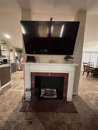 a living room with a fireplace a flat screen tv and kitchen view