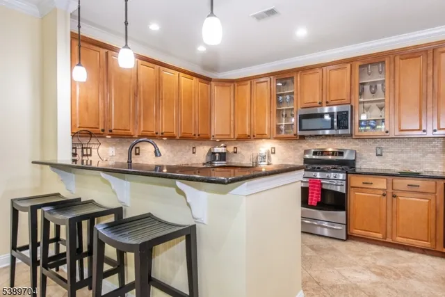 a kitchen with stainless steel appliances granite countertop a stove a sink dishwasher and a microwave oven with cabinets