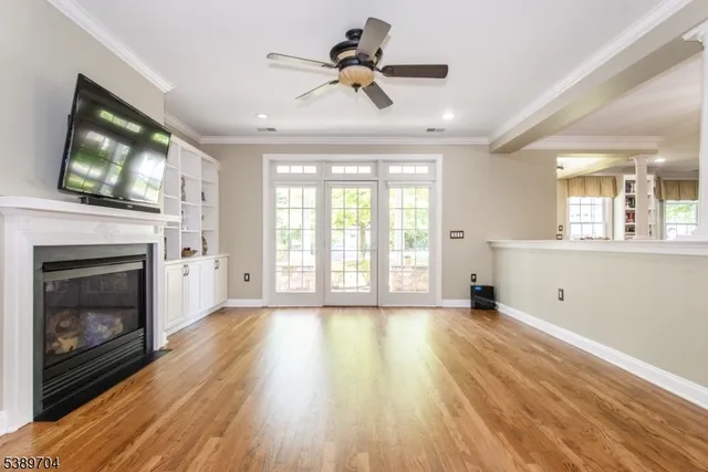 a view of an empty room with wooden floor and a fireplace