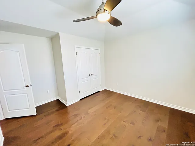 an empty room with wooden floor cabinet and ceiling fan