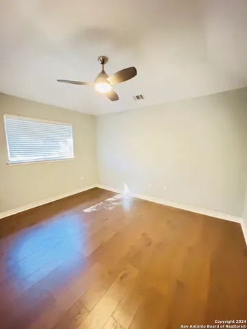 an empty room with a window and ceiling fan