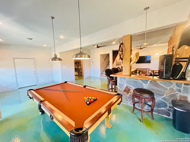 a room with pool table and chairs