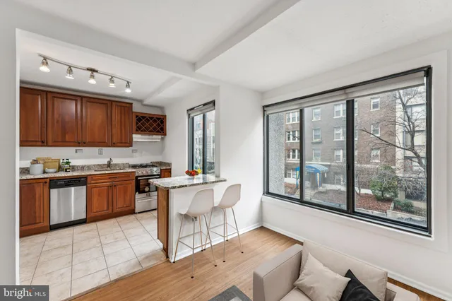 a kitchen with stainless steel appliances granite countertop a stove top oven a sink dishwasher a dining table and chairs with wooden floor