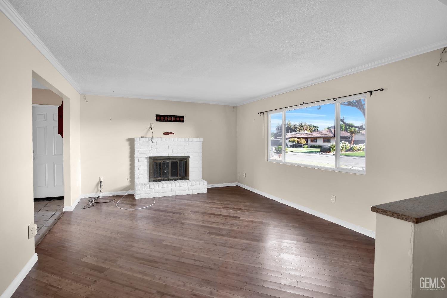 Undisclosed Address Bakersfield, CA 93312 - Photo 3 of 26 an empty room with wooden floor and a fireplace