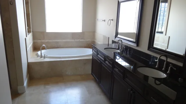 a bathroom with a double vanity sink a mirror and bathtub