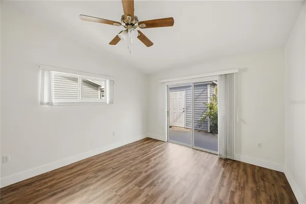 an empty room with wooden floor fan and windows