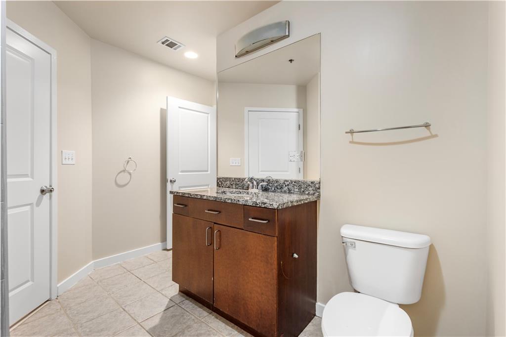 250 Pharr Road Northeast, Unit 308 Atlanta, GA 30305 - Photo 14 of 35 a bathroom with a granite countertop toilet sink and mirror