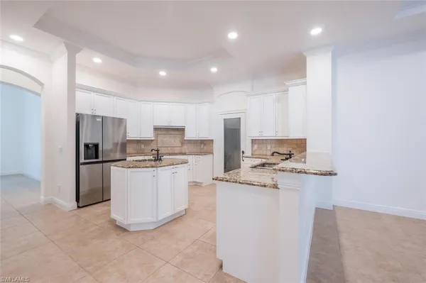 a kitchen with a refrigerator a stove top oven and white cabinets