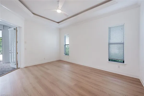 an empty room with wooden floor cabinet and windows