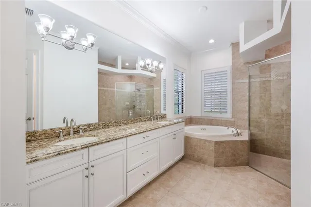 a spacious bathroom with a granite countertop double vanity sink a large mirror and a bathtub