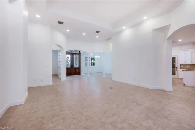 an empty room with kitchen view and a window