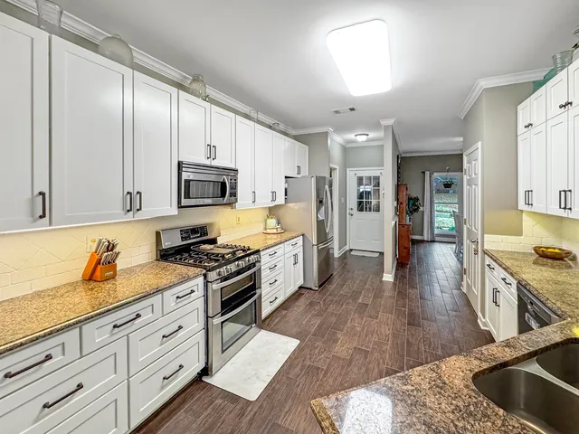 a kitchen with granite countertop a stove a sink and a refrigerator