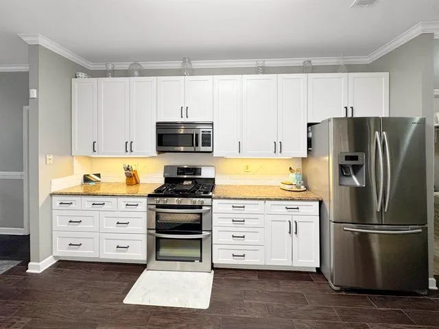 a kitchen with stainless steel appliances a refrigerator stove and white cabinets