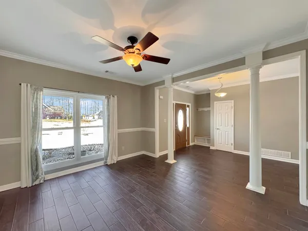 an empty room with a chandelier fan and view of a bathroom