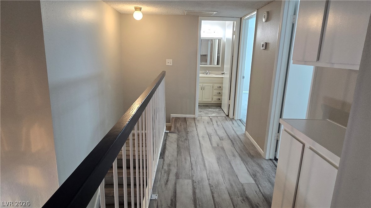 3849 Reflection Way Las Vegas, NV 89147 - Photo 16 of 25 This upper-level hallway features wood-look flooring and a safety railing, leading to a pristine bathroom.