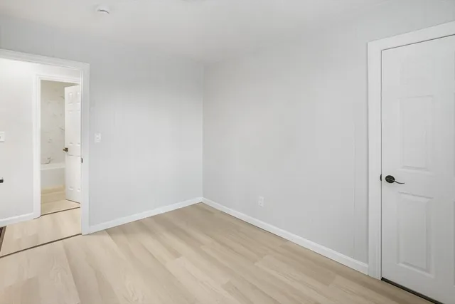 a view of an empty room with a window and a painting on the wall