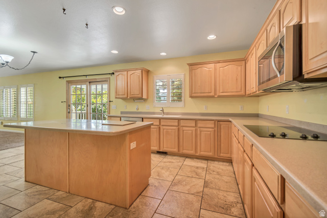 546 Wheatridge Road Tooele, UT 84074 - Photo 14 of 49 Open-concept kitchen featuring an island with countertop seating, wood-finish cabinetry, tile flooring, and sliding glass door