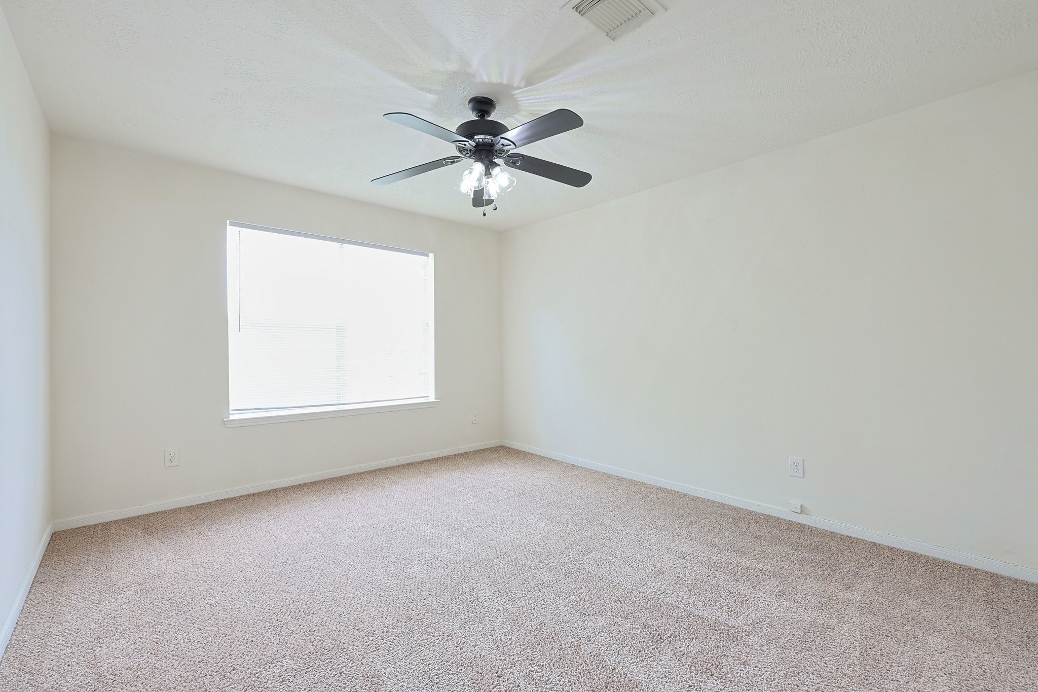 23019 Eastgate Village Drive Spring, TX 77373 - Photo 35 of 46 spacious Bedroom 4 with neutral carpeting, a large window for natural light, and a ceiling fan. Ideal for a bedroom or office space.