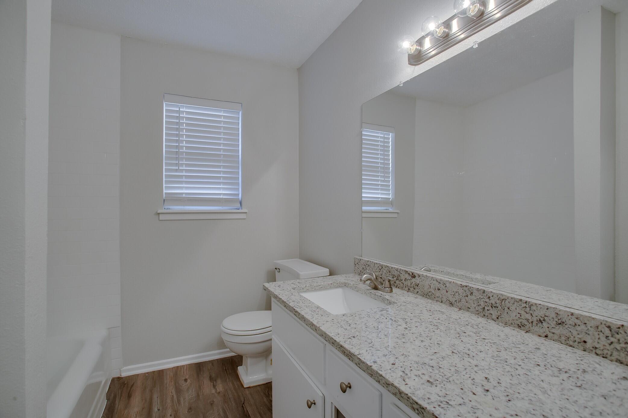 5419 46th Street Lubbock, TX 79414 - Photo 13 of 14 a bathroom with a granite countertop sink a toilet and a window