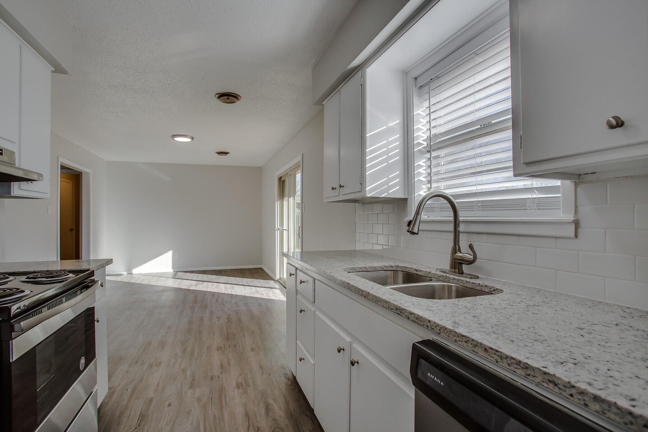 5419 46th Street Lubbock, TX 79414 - Photo 6 of 14 a kitchen with granite countertop a sink and a stove top oven