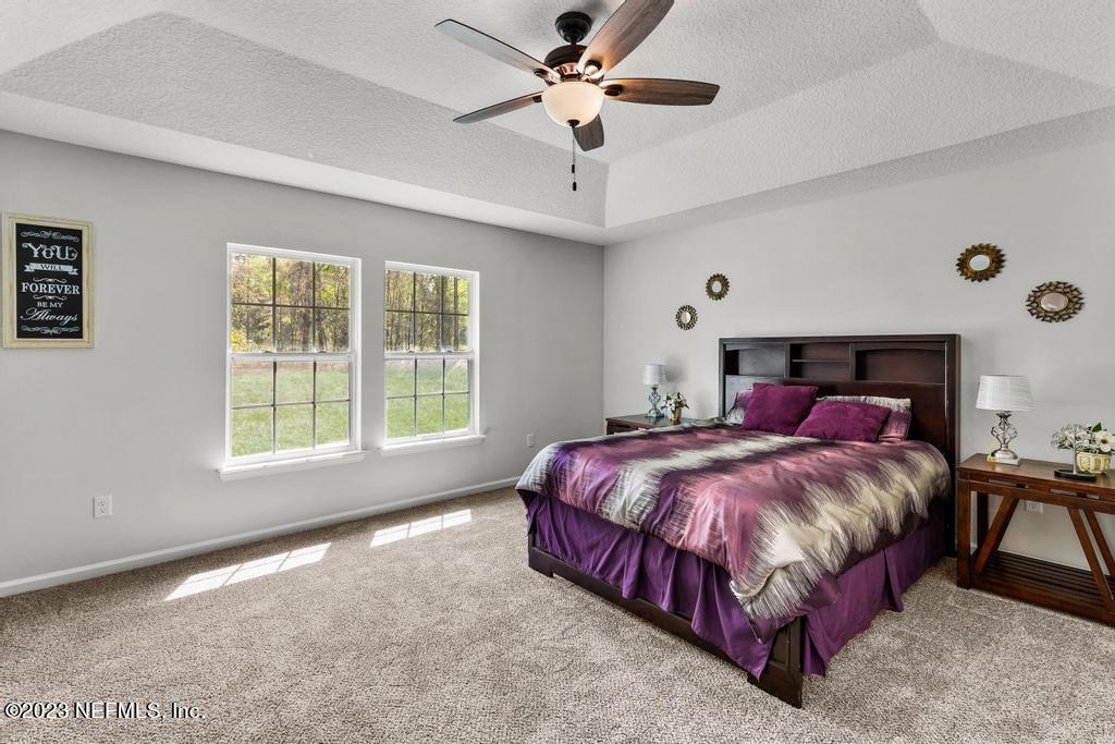 54150 Deerfield Country Club Road Callahan, FL 32011 - Photo 21 of 37 a spacious bedroom with a bed and a chandelier
