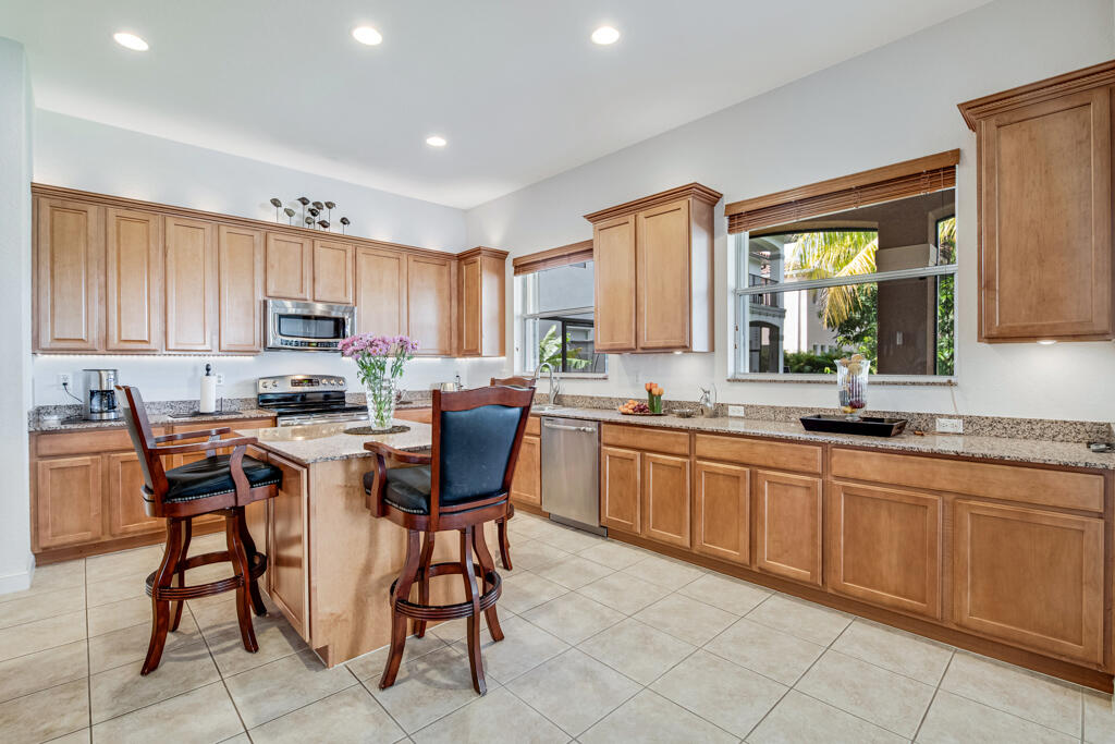514 Cresta Circle West Palm Beach, FL 33413 - Photo 20 of 74 a kitchen with stainless steel appliances granite countertop wooden cabinets a table and chairs
