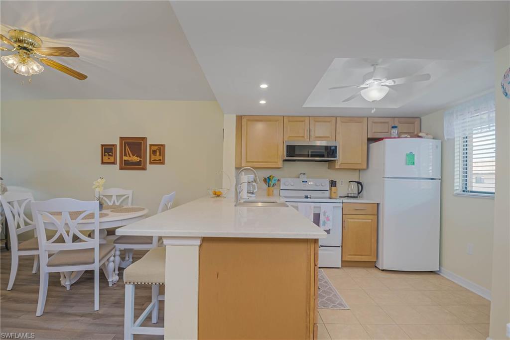 4790 South Cleveland Avenue, Unit 607 Fort Myers, FL 33907 - Photo 7 of 21 a kitchen with refrigerator a stove a sink and chairs