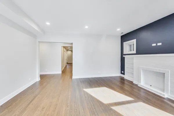 a view of an empty room with wooden floor and a fireplace