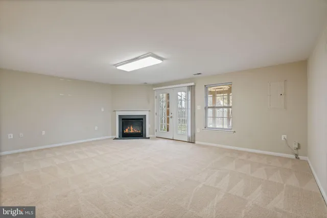 an empty room with windows and fireplace
