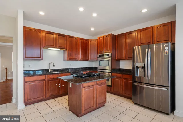 a kitchen with stainless steel appliances granite countertop a refrigerator a sink a stove top oven and cabinets