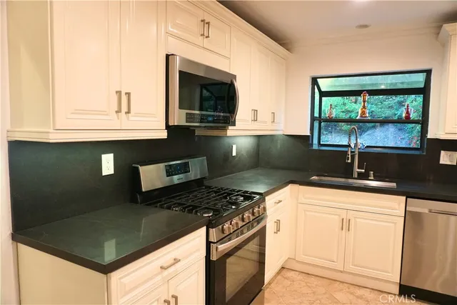 a kitchen with granite countertop a sink stainless steel appliances a counter space and cabinets