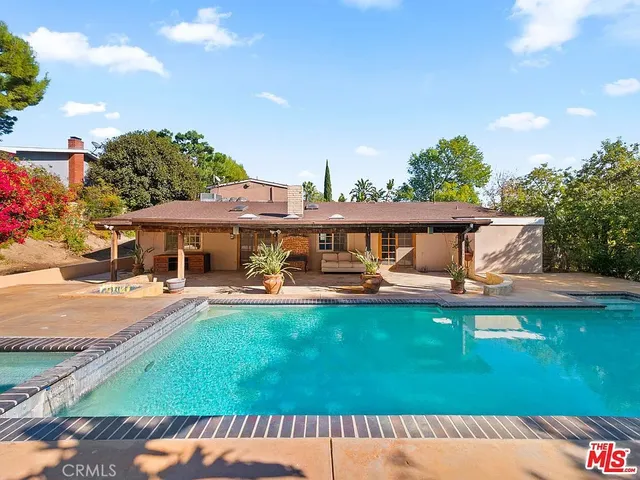 a view of a swimming pool with lawn chairs under an umbrella