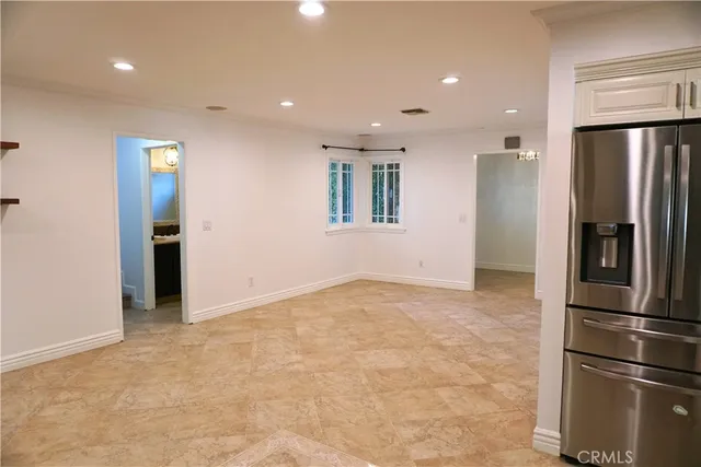 a view of an empty room with window and stainless steel appliances