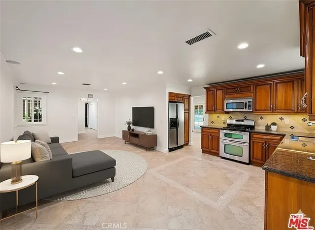 a large living room with stainless steel appliances kitchen island granite countertop a couch and a view of living room