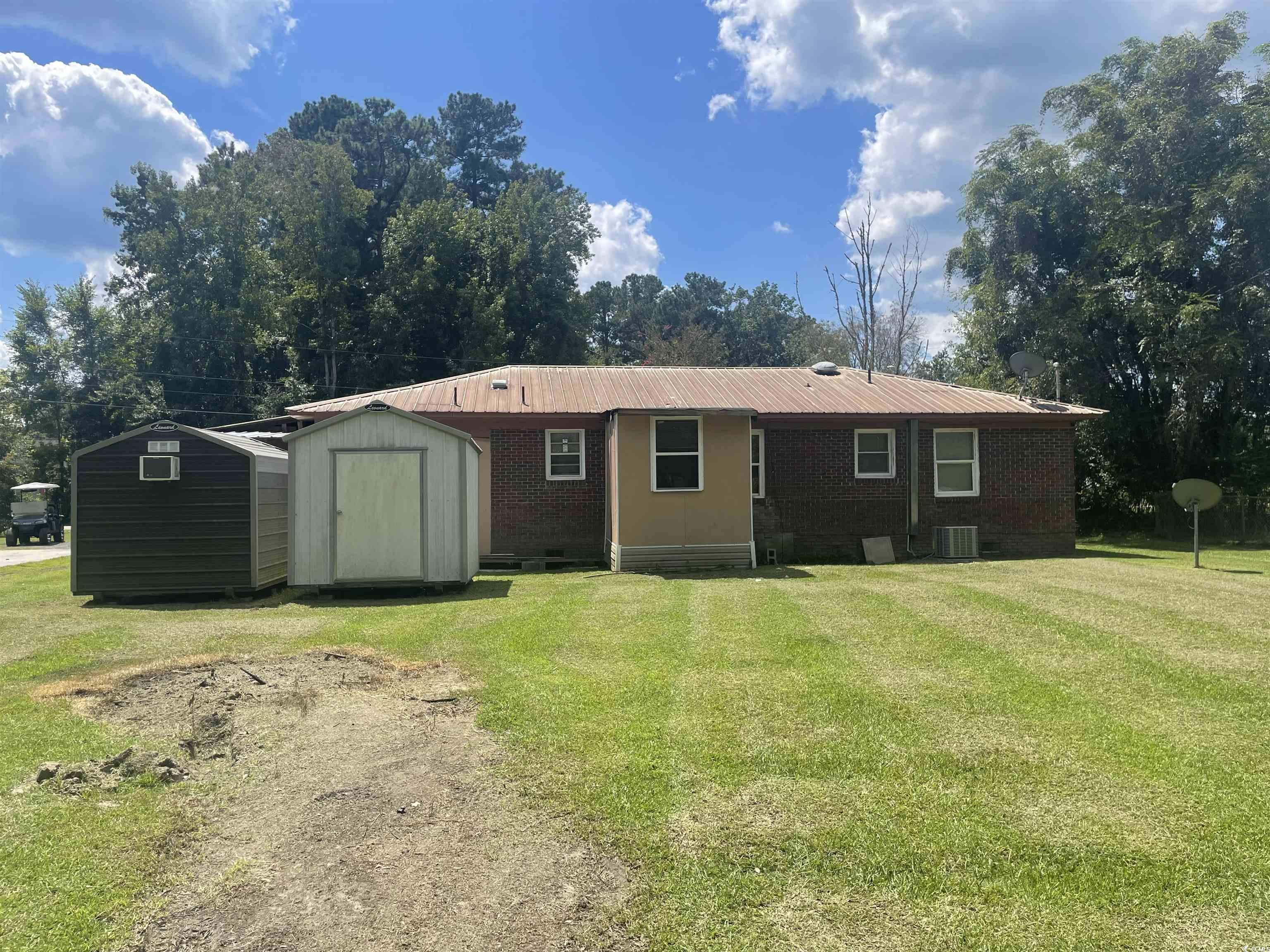 704 West Alder Street Andrews, SC 29510 - Photo 12 of 12 Rear view of house featuring a storage shed, brick siding, a lawn, and a metal roof